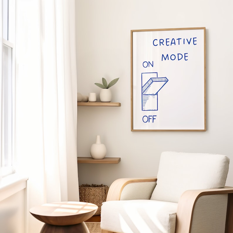 Może przedstawiać: Biały wydruk w ramie z tekstem "CREATIVE MODE" i niebieską ilustracją przełącznika w pozycji "włączony". Wydruk wisi na białej ścianie.