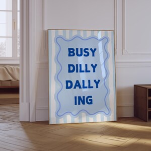 May include: A blue and white striped poster with the text "BUSY DILLY DALLY ING" in a blue wavy frame.