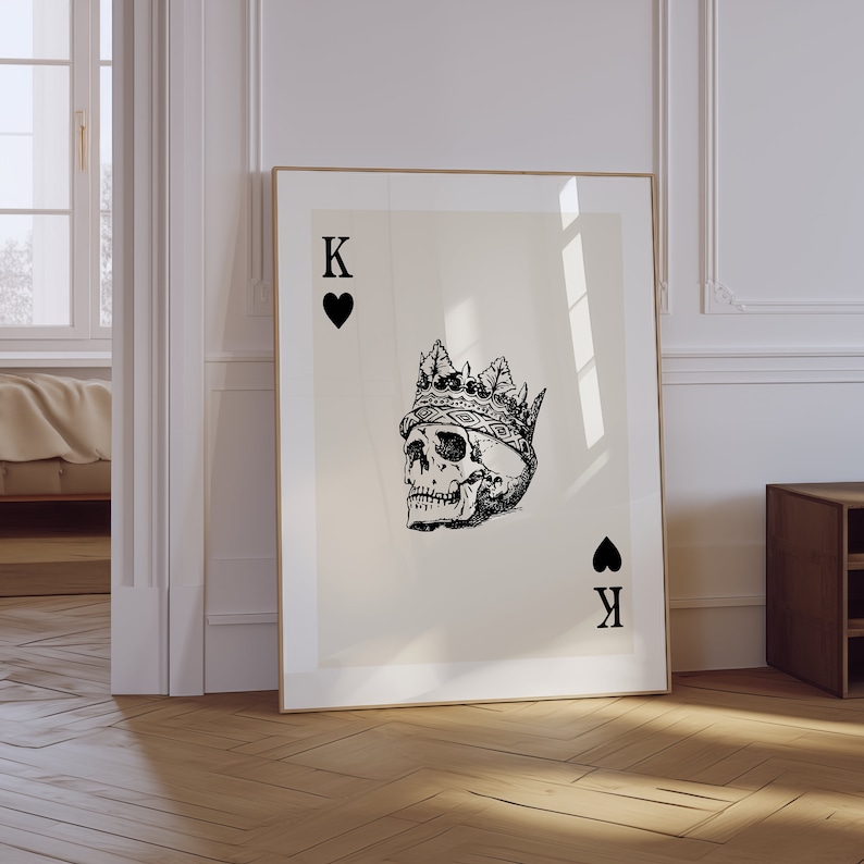 May include: A black and white illustration of a skull wearing a crown, with the letters 'K' and a heart symbol in the top left corner and the letters 'K' and a spade symbol in the bottom right corner.