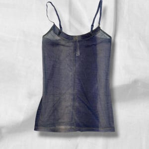 Op de afbeelding: Een mouwloze camisole-top van donkerblauwe stof met een denim-look. Het kledingstuk is voorzien van dunne verstelbare schouderbandjes, een ronde halslijn met een enkel knoopdetail in het midden en zichtbare stiksels langs de naden.