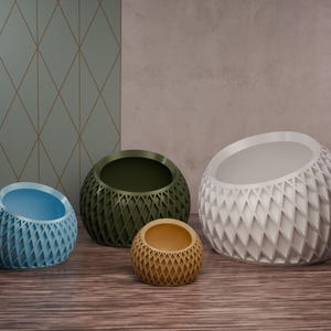 May include: Four decorative planters in different sizes and colours. The planters are made of a textured material and have a geometric design. The planters are arranged in a row on a wooden surface.