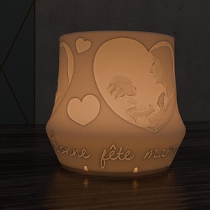 Op de afbeelding: Witte keramische lamp met een hartvormig ontwerp en een foto van een moeder en kind. De lamp heeft de tekst "bonne fête maman" op de bodem.