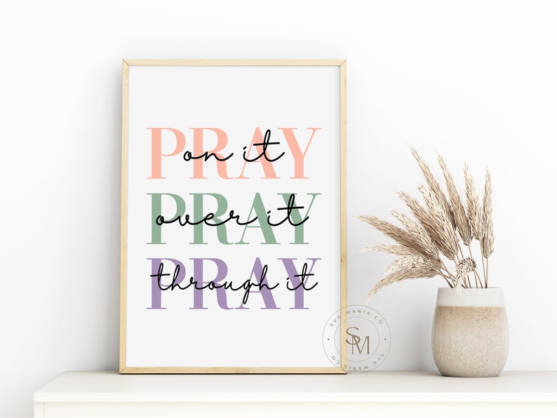 May include: A framed print with the text "Pray on it, Pray over it, Pray through it" in pink, green, and purple lettering. The print is on a white background and has a gold frame.