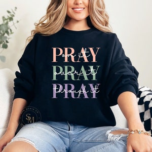 May include: A black sweatshirt with the text "PRAY on it PRAY over it PRAY through it" in pink, green, and purple lettering.
