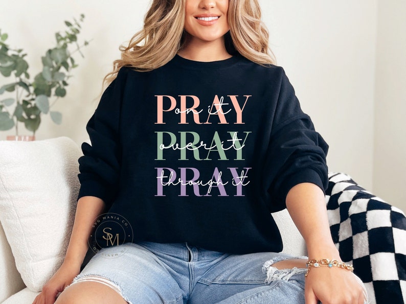 May include: A black sweatshirt with the text "PRAY on it PRAY over it PRAY through it" in pink, green, and purple lettering.