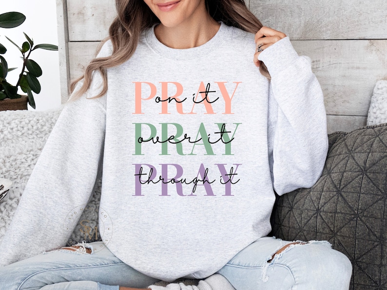 May include: A gray sweatshirt with the text "Pray on it, Pray over it, Pray through it" in pink, green, and purple lettering.