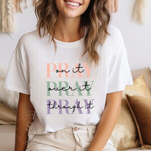 May include: White t-shirt with the text "Pray on it, Pray over it, Pray through it" in colorful lettering.
