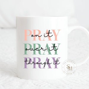 May include: White ceramic mug with the text "Pray on it, Pray over it, Pray through it" in pink, green, and purple lettering. The text is centered on the mug. The mug has a black handle.