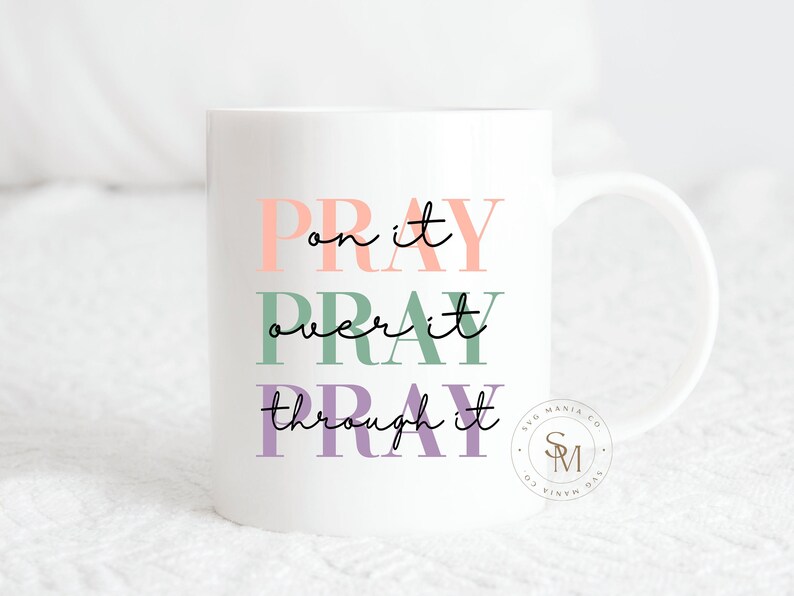 May include: White ceramic mug with the text "Pray on it, Pray over it, Pray through it" in pink, green, and purple lettering. The text is centered on the mug. The mug has a black handle.