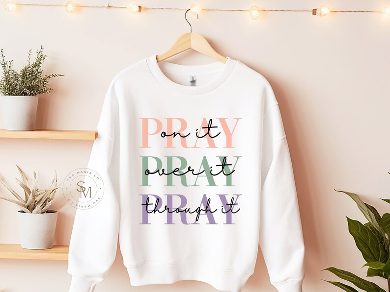 May include: White sweatshirt with the text "PRAY on it PRAY over it PRAY through it" in pink, green, and purple lettering.