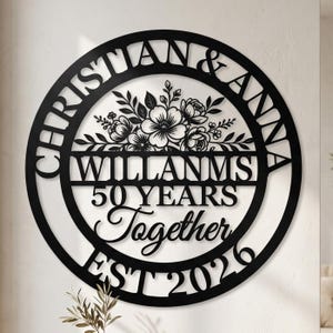 May include: Black metal wall art featuring the names "CHRISTIAN & ANNA" and "WILLANMS" with "50 YEARS Together EST 2026" in a circular design. The design includes floral accents in the centre.