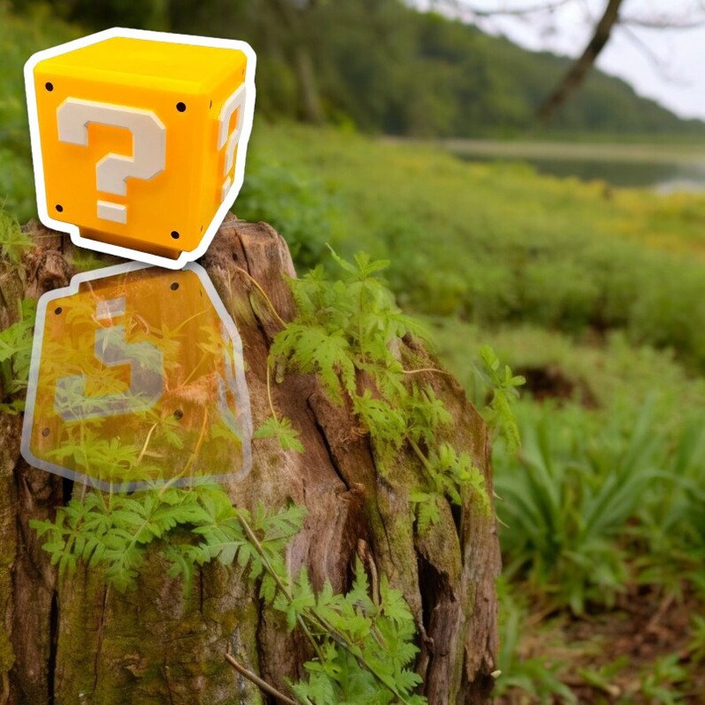 May include: A yellow cube with a white question mark on each side, reminiscent of a video game item. The cube is set against a natural backdrop of a tree stump and lush greenery, creating a playful contrast.