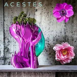 以下が含まれることがあります： マゼンタ色の彫刻。顔が両手を広げ、ターコイズブルーのオーブを持ち、緑の植物で満たされている。上部には「ACESTES」の文字。右側には、ピンクのシャクヤクと紫のアネモネの2つの花がある。