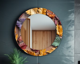 May include: A round mirror with a decorative frame of colorful autumn leaves. The mirror is hanging on a dark blue wall in a bathroom setting.