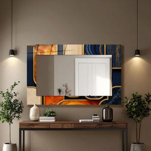 May include: A rectangular wall mirror featuring a decorative border with an abstract pattern of deep blue, orange, and cream tones. The frame displays a mix of marble-like textures and gold-colored lines, surrounding a clear, reflective glass center.