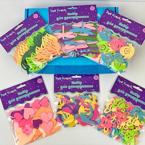 May include: A collection of colorful foam cutouts for decoration, including leaves, dragonflies, hearts, and flowers. The cutouts are packaged in clear plastic bags with purple labels that read "Apli Krapi Набір для декорування". The set is presented in a blue box.