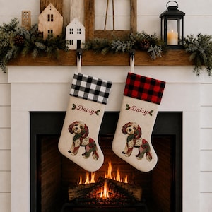 May include: Two beige Christmas stockings featuring a dog illustration and the name Daisy embroidered in red. One stocking has a black and white buffalo check cuff, while the other has a red and black buffalo check cuff, both hanging by loops.