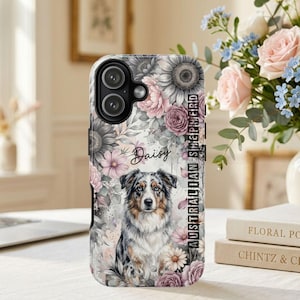 May include: A phone case featuring a watercolour-style illustration of an Australian Shepherd dog surrounded by pink and grey flowers. The name Daisy is written in cursive script above the dog, and the text AUSTRALIAN SHEPHERD is printed vertically.