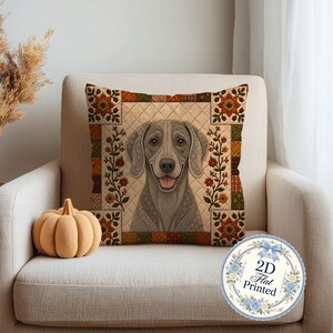 May include: A square throw pillow featuring a central illustration of a grey dog with a smiling expression. The pillow has a quilted-style background with a border of autumn-colored floral and plaid squares in shades of orange, brown, and green.
