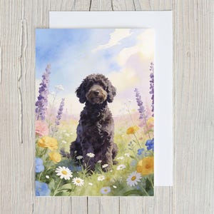 May include: A watercolor greeting card featuring a black dog sitting in a field of colorful wildflowers. The dog has curly fur and is looking directly at the viewer. The background includes a blue sky with fluffy clouds and various flowers.