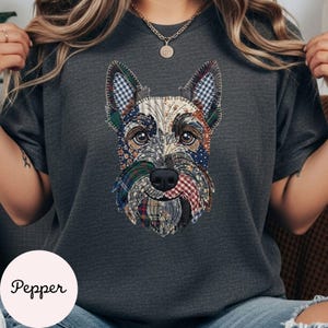 May include: Dark gray t-shirt featuring a patchwork design of a Scottish Terrier's face. The dog's face is composed of various fabric patterns, including plaid and floral prints. The word "Pepper" is printed on a white circle at the bottom left.