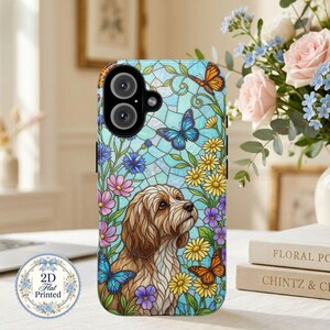 May include: A phone case featuring a stained glass style design with a light brown dog surrounded by colorful butterflies and flowers in shades of blue, yellow, and pink. The case has a black camera cutout and a 2D flat printed finish.