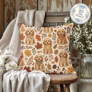 May include: A square throw pillow featuring a repeating pattern of golden-brown doodle dogs wearing patterned bandanas, interspersed with autumn leaves, acorns, and pinecones on a cream background. A circular sticker reads 2D Flat Printed.
