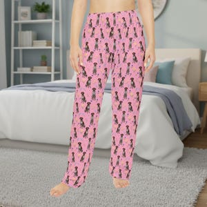 Könnte beinhalten: Rosa Schlafanzughose mit einem sich wiederholenden Muster aus braunen Hunden, lila Blumen und gelben Herzen. Die Hose ist aus einem weichen Material gefertigt und auf Komfort ausgelegt. Eine lustige und verspielte Ergänzung für jede Nachtwäschekollektion.