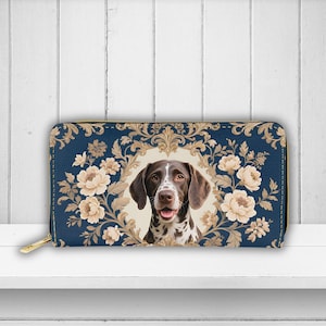May include: A navy blue zippered wallet featuring a German Shorthaired Pointer dog portrait surrounded by cream-colored floral elements. The wallet has a gold-colored zipper and a floral pattern.