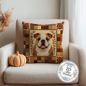 Peut inclure: Un coussin carré orné d'un portrait central de bouledogue marron et blanc avec la langue sortie, encadré par des vignes fleuries. La bordure présente un motif patchwork dans des tons orange, marron et jaune. Un badge circulaire indique 2D Flat Printed.