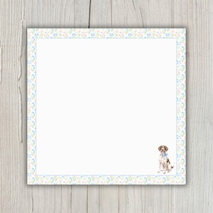 May include: Square white notepad with a floral border in pastel blue, pink, and green. A watercolor illustration of a brown and white dog with a blue bow tie is in the lower right corner.