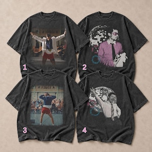 May include: Four charcoal gray short-sleeve t-shirts with graphic prints. Shirt 1 and 3 show a person in a white blazer or blue jacket with red shorts. Shirt 2 and 4 feature a person with a disco ball, pink glasses, and text accents.