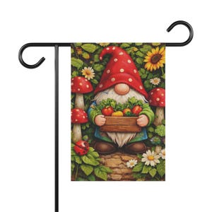 May include: A garden flag featuring a gnome with a red hat and white polka dots, holding a wooden crate filled with vegetables. The flag has a black metal stand and is surrounded by mushrooms, flowers, and greenery.