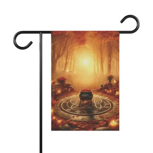 May include: A Halloween-themed garden flag with a cauldron in the center of a circle with a pentagram design. The cauldron is filled with red leaves and is surrounded by candles and other autumnal decorations. The background is a misty forest with a golden glow.