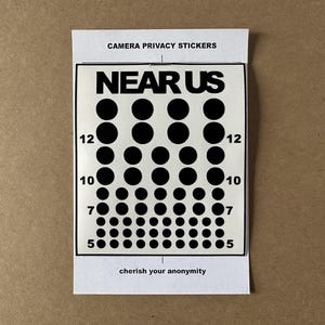 Op de afbeelding: Een witte kaart met zwarte tekst die "CAMERA PRIVACY STICKERS" en "NEAR US" zegt. De kaart toont een zwart-witte afbeelding van een reeks cirkels die in een piramidevorm zijn gerangschikt. De cirkels zijn gelabeld met de nummers 5, 7, 10 en 12. De onderkant van de kaart luidt "cherish your anonymity".
