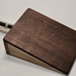 May include: A wooden foot pedal with a dark brown top and a light brown bottom. The pedal has a single input jack on the side.