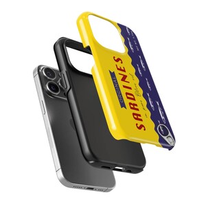 Tough Phone case designed as a vintage sardine tin can with silver fish illustration and pull-tab detail on a bold yellow and navy background – retro foodie aesthetic.