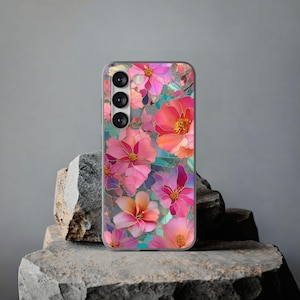 May include: A phone case featuring a floral design with pink, coral, and purple flowers. The flowers have gold outlines and are set against a teal and purple background. The case has a camera module with three lenses.