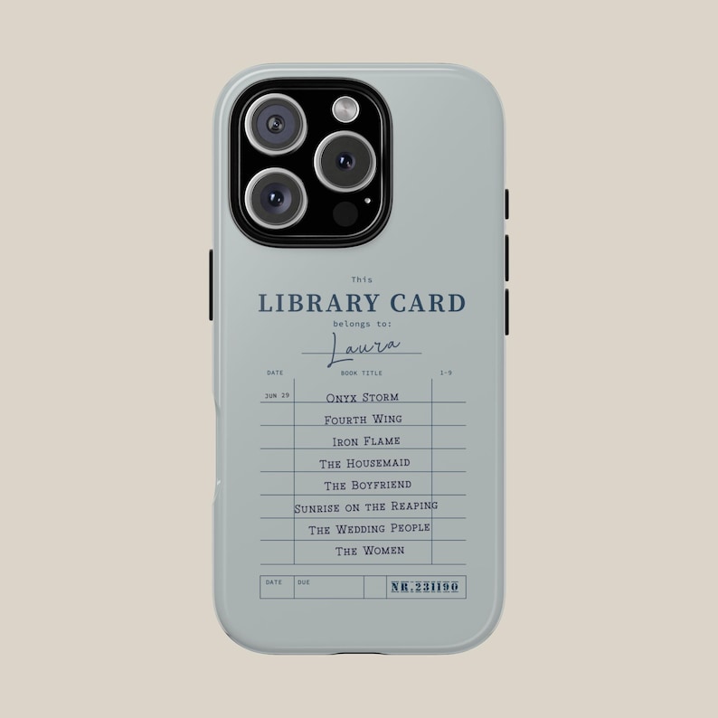 May include: A light gray phone case featuring a library card design. The text reads "This LIBRARY CARD belongs to: Laura" with a list of book titles. The case has a camera cutout and black accents on the sides.