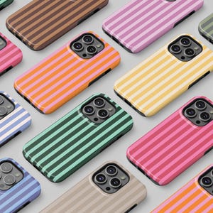 Puede incluir: Una colección de fundas para teléfonos con patrones de rayas verticales. Las fundas presentan varios colores, incluyendo rosa, naranja, amarillo, verde, azul y marrón. Cada funda tiene un recorte para la cámara y un borde negro.