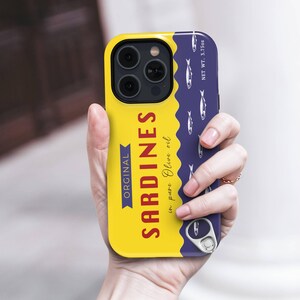 Phone case designed as a vintage sardine tin can with silver fish illustration and pull-tab detail on a bold yellow and navy background – retro foodie aesthetic.