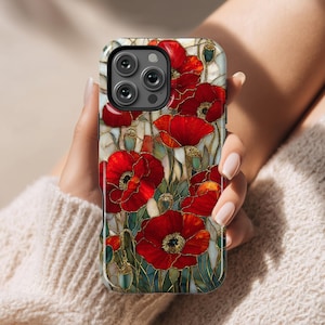 Op de afbeelding: Een smartphonehoesje met een glas-in-lood ontwerp van rode klaprozen met groene bladeren en gouden contouren. De hoes heeft een zwarte rand en wordt door een persoon vastgehouden.