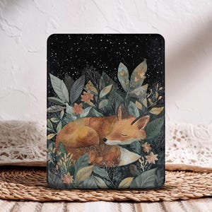 Puede incluir: Una funda negra para tableta con una ilustración en acuarela de un zorro durmiendo entre un exuberante follaje verde y marrón. El fondo es un cielo estrellado. La funda tiene forma rectangular.