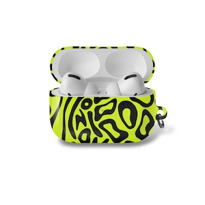 以下が含まれることがあります： ネオンの緑と黒の抽象的な模様のAirPods Proケースが開いています。ケースには白いAirPodsが2つ入っています。ケースの側面には小さなシルバーのリングが付いています。