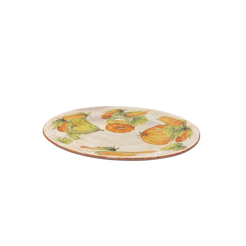 May include: Oval serving platter with a hand-painted design of corn, squash, and other vegetables. The rim is a warm brown, and the background is a creamy off-white. A decorative piece for the kitchen or dining room.