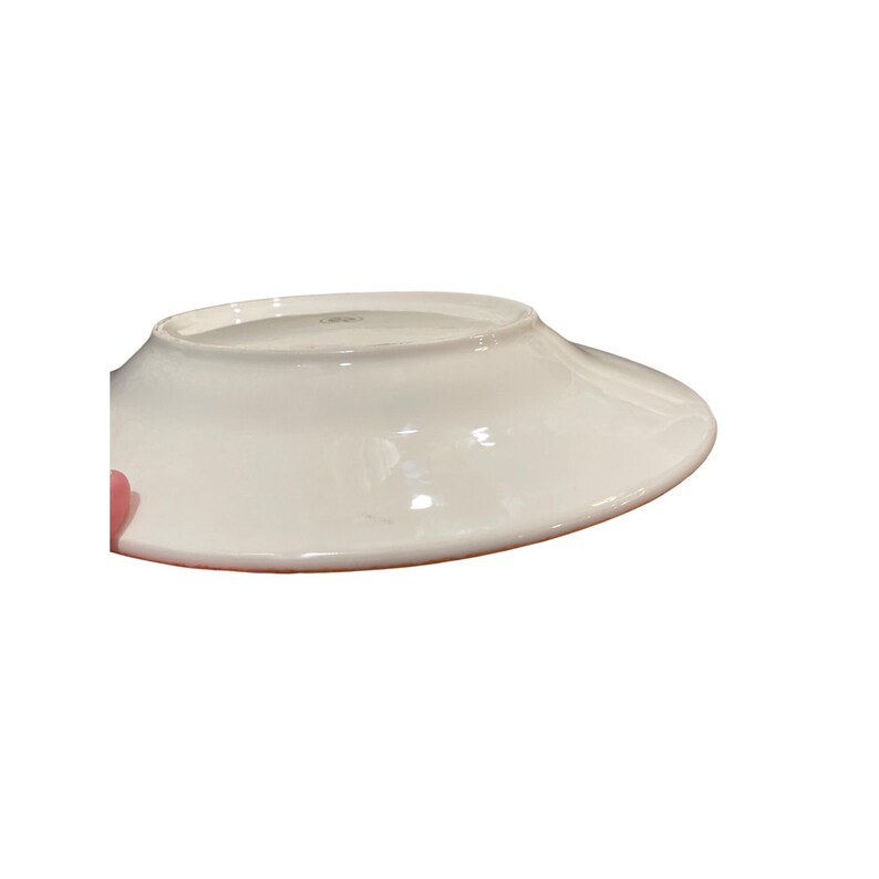 May include: A white ceramic plate with a wide, slightly curved rim. The plate is glossy and appears to be clean. The underside of the plate is visible, showing the rim's shape and the plate's overall design. The plate is likely for serving food.