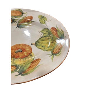 May include: A decorative ceramic serving platter with a painted harvest theme. The platter features images of pumpkins, corn on the cob, and gourds in shades of orange, yellow, and green. The rim has a brown border.
