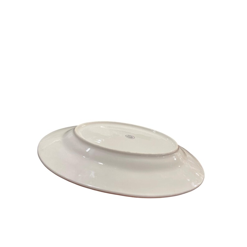 May include: A white, oval-shaped ceramic serving platter. The underside of the platter is visible, showcasing a smooth, glossy surface and a subtle rim. The platter is designed for serving food.