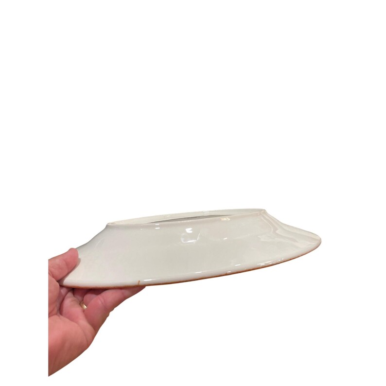 May include: A white ceramic plate with a slightly raised rim and a brown edge. The plate is held by a hand, showcasing its clean design and simple elegance. Ideal for serving food.