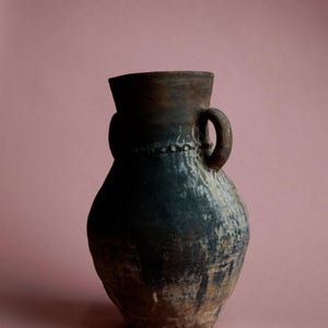 May include: A dark brown ceramic jug with a single handle and a textured surface. The jug has a wide mouth and a rounded body.